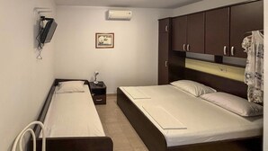 A small, clean room with two single beds, a nightstand, a wall-mounted air conditioner, and a framed picture. - Stunning apartment in Drvenik with house sea view (Drvenik)