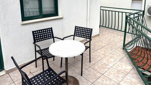 A small outdoor patio with a round table and four chairs, a window with blinds, and a green metal railing. - Stunning apartment in Drvenik with house sea view (Drvenik)