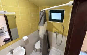 A bathroom with yellow tiles, a white sink, a toilet, a shower, and a mirror. - Stunning apartment in Drvenik with house sea view (Drvenik)