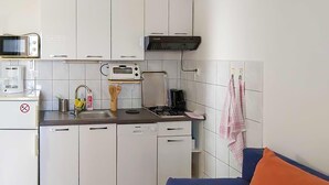 A compact kitchen with white cabinets, a microwave, a coffee maker, and a stove. - Cozy apartment in Zivogosce with WiFi (Zivogosce)