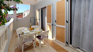A balcony with a table set for two, chairs, and a bottle of wine. - Cozy apartment in Zivogosce with WiFi (Zivogosce)