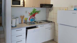 Una cocina con armarios blancos, microondas, fregadero y refrigerador.