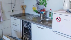 Una cocina con lavavajillas, un fregadero, cafetera y una planta sobre la encimera.