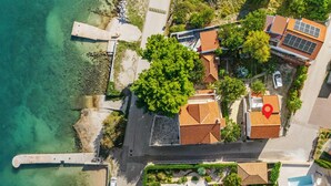 An aerial view of a coastal property with multiple buildings, a swimming pool, and a dock.