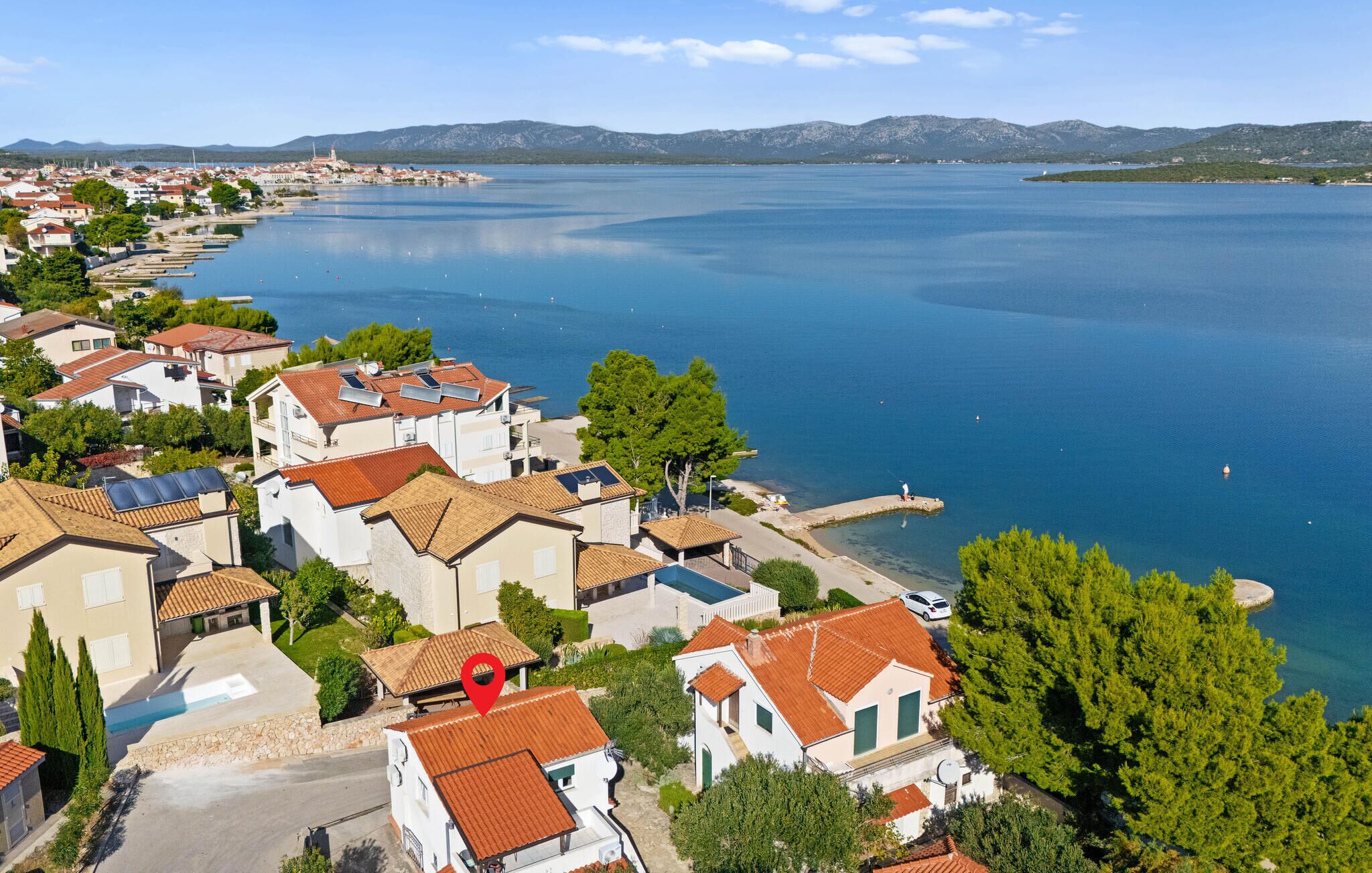 A coastal residential area with houses, a marina, and a clear view of the sea.
