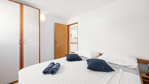 A hotel room with a bed, pillows, a wooden wardrobe, and a mirror.