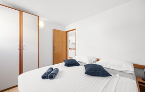 Una habitación de hotel con cama, almohadas, un armario de madera y un espejo.
