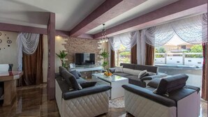 Un salon moderne avec un téléviseur, deux canapés, une table basse et un mur d’accent en pierre.