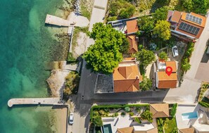 Vista aérea de una propiedad costera con varias edificaciones, una piscina y un muelle.