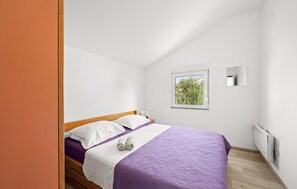 Un dormitorio con cama, ventana con vistas, luz empotrada en la pared y radiador.