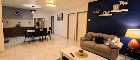A modern living room with a sofa, coffee table, and dining area.