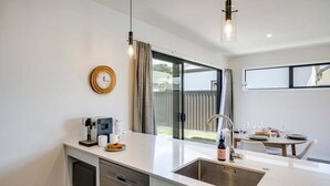 Una cocina moderna con lavavajillas integrado, cafetera y pileta.