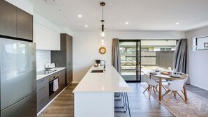 Una cocina moderna con una isla central, electrodomésticos de acero inoxidable y un comedor con mesa y sillas.