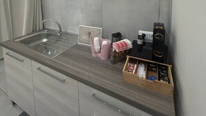Een kleine keuken met een spoelbak, een koffieapparaat en een kastje met keukenbenodigdheden.