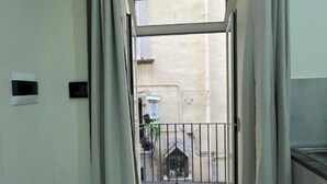 Een smalle gang met uitzicht op een balkon en een gebouw.