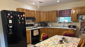 A kitchen with wooden cabinets, a black refrigerator, a microwave, and a dining table with a floral tablecloth. - 2 bed 2 bath home in Ocala Fl
Front porch
Screened back porch
Cozy home (Ocala)