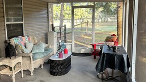 A covered porch with a wicker sofa, a round coffee table, and a small table with a black tablecloth. - 2 bed 2 bath home in Ocala Fl
Front porch
Screened back porch
Cozy home (Ocala)