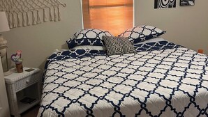 A bedroom with a bed, a nightstand, a macrame wall hanging, a window with blinds, and wall art. - 2 bed 2 bath home in Ocala Fl
Front porch
Screened back porch
Cozy home (Ocala)