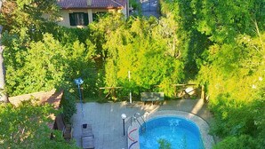 A circular swimming pool with a hot tub, surrounded by a patio area with a bench and a lamp post.