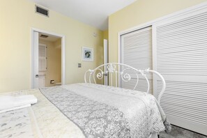 A bedroom with a bed, a white metal headboard, a door, and a wall-mounted air vent. - Beautiful Naples Vacation Rental w/ Shared Pools (Naples)