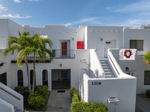 Exterior view of white multi-level units featuring outdoor stairs and tropical landscaping. - Beautiful Naples Vacation Rental w/ Shared Pools (Naples)