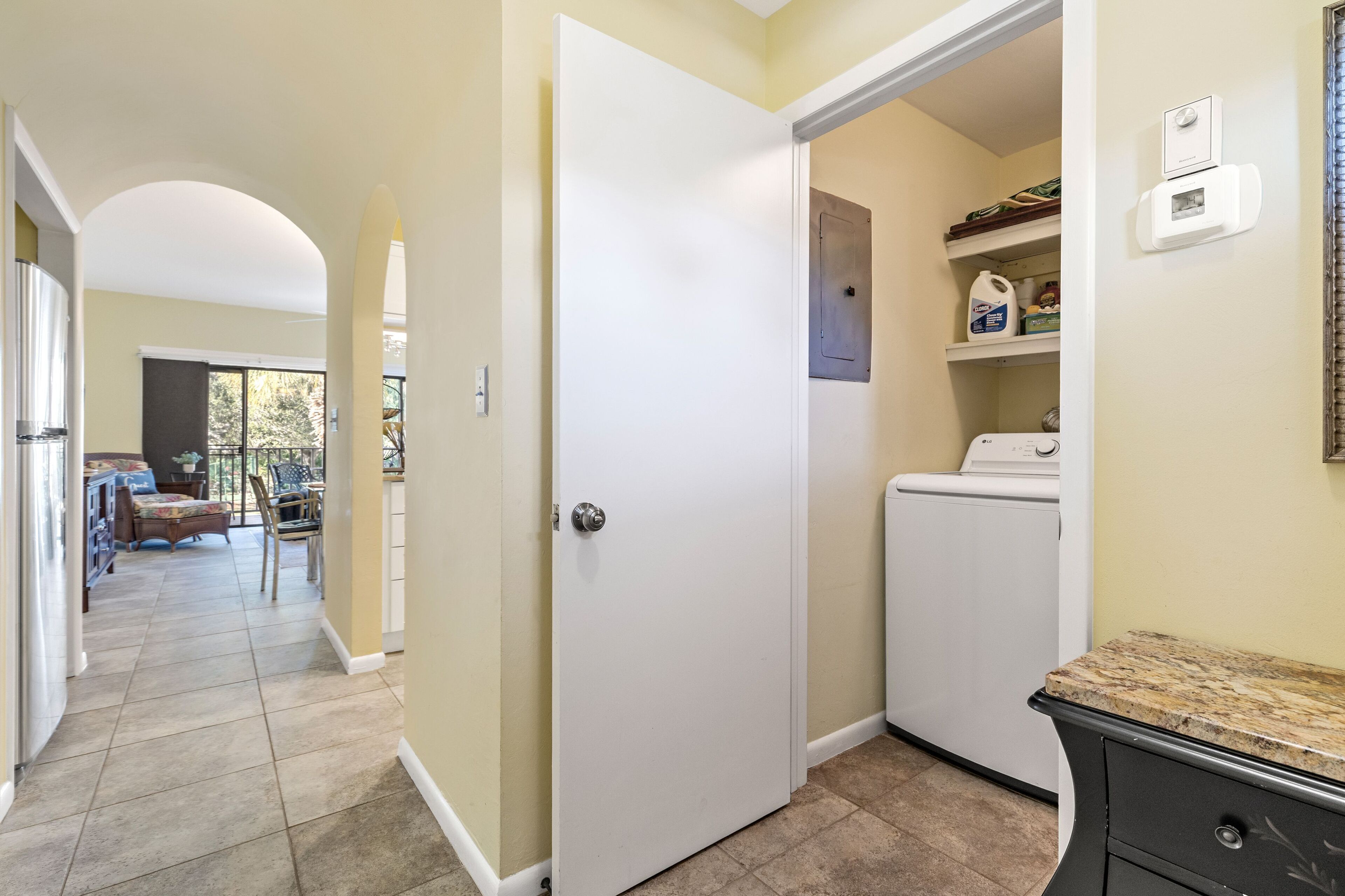 A laundry room with a washing machine, a dryer, and shelves with cleaning supplies.