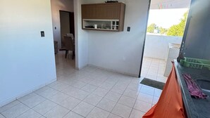 Ein geräumiges Zimmer mit Fliesenboden, einer eingebauten Holzkabine, einer Tür zu einem anderen Raum und einem Balkon mit Blick.