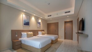 A hotel room with two beds, a wooden headboard, a mounted TV, and a large wardrobe.