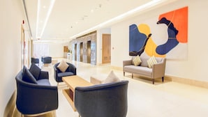 A modern lobby with seating areas, a reception desk, and a large abstract artwork on the wall.