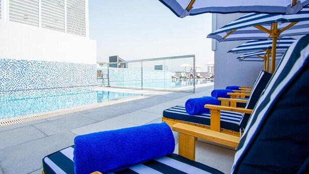 A rooftop pool area with lounge chairs and umbrellas.