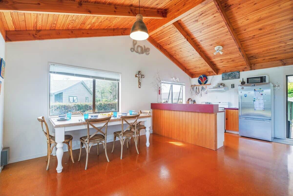 A kitchen with a wooden ceiling, a dining area with a table and chairs, and a refrigerator.