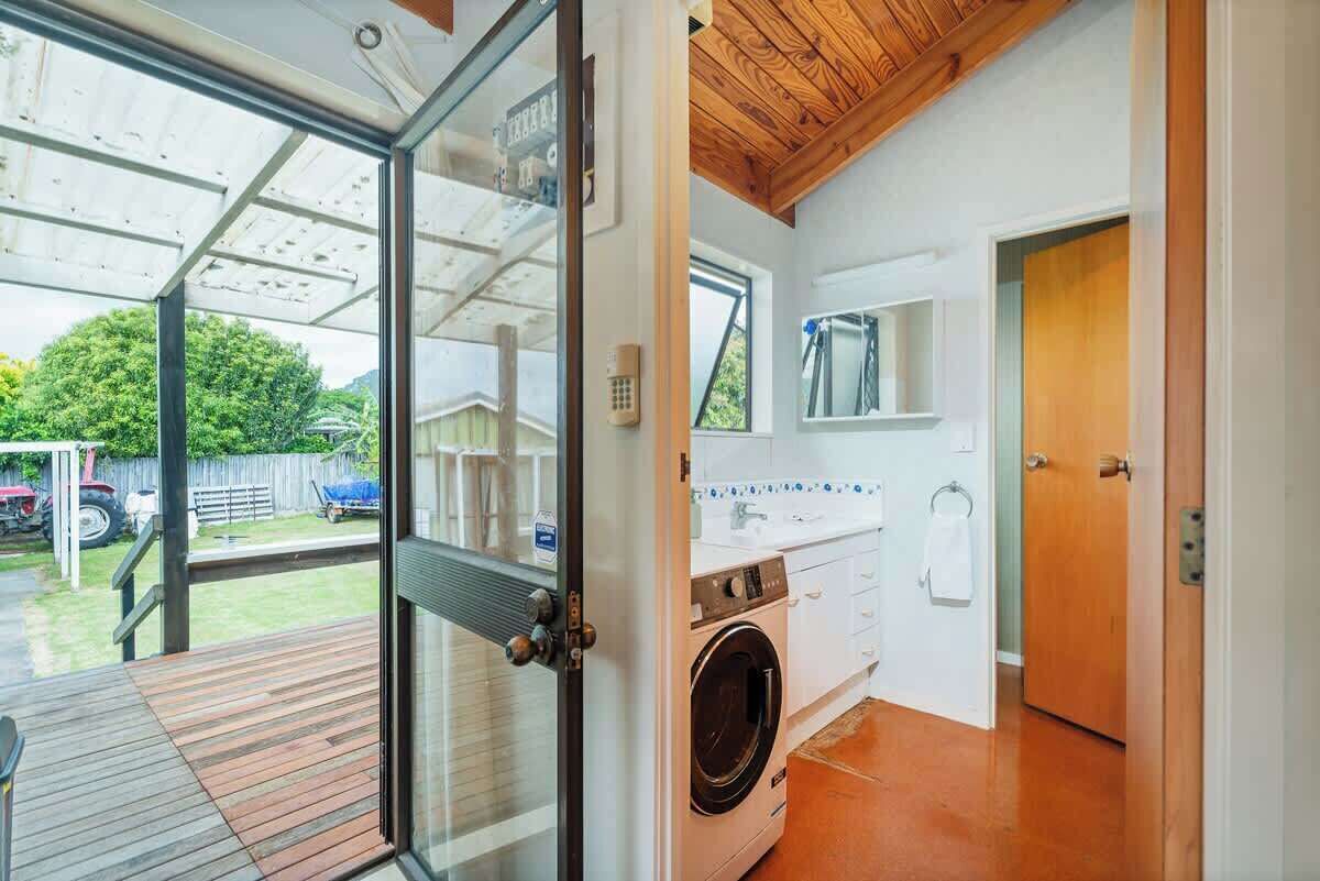 A modern kitchen with a built-in washing machine, a wooden ceiling, and a glass door leading to an outdoor area.