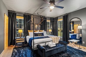 Ein modernes Schlafzimmer mit einem großen Bett, einem Deckenventilator und Blick ins Freie.
