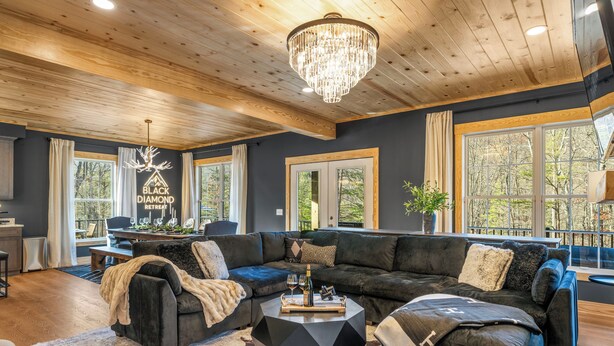 A modern living room with a dark gray sofa, a round coffee table, and a chandelier. - Black Diamond Retreat 7BR Sleeps 18 Hot Tub+Sauna 3 Min to Massanutten Slopes (McGaheysville)