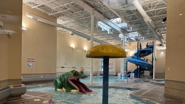Ein Indoor-Wasserpark mit einer großen Froschskulptur, einer Rutsche und einem Whirlpoolbereich.