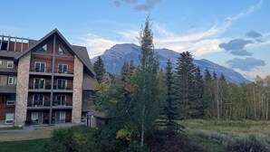 Eine mehrstöckige Lodge mit Steinfassade, mehreren Balkonen und Blick auf Berge im Hintergrund.