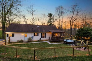 Ein eingeschossiges Haus mit überdachter Veranda, Whirlpool und umzäunter Garten.