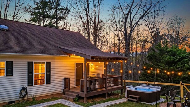 Ein Haus mit einer Veranda, einem Whirlpool und einer Terrasse mit Lichterketten.