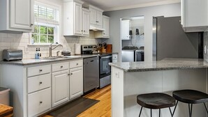 Eine moderne Küche mit weißen Schränken, Granit Arbeitsplatten, Edelstahlgeräten und Holzboden.