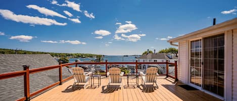 A wooden deck with outdoor seating and a view of the water.