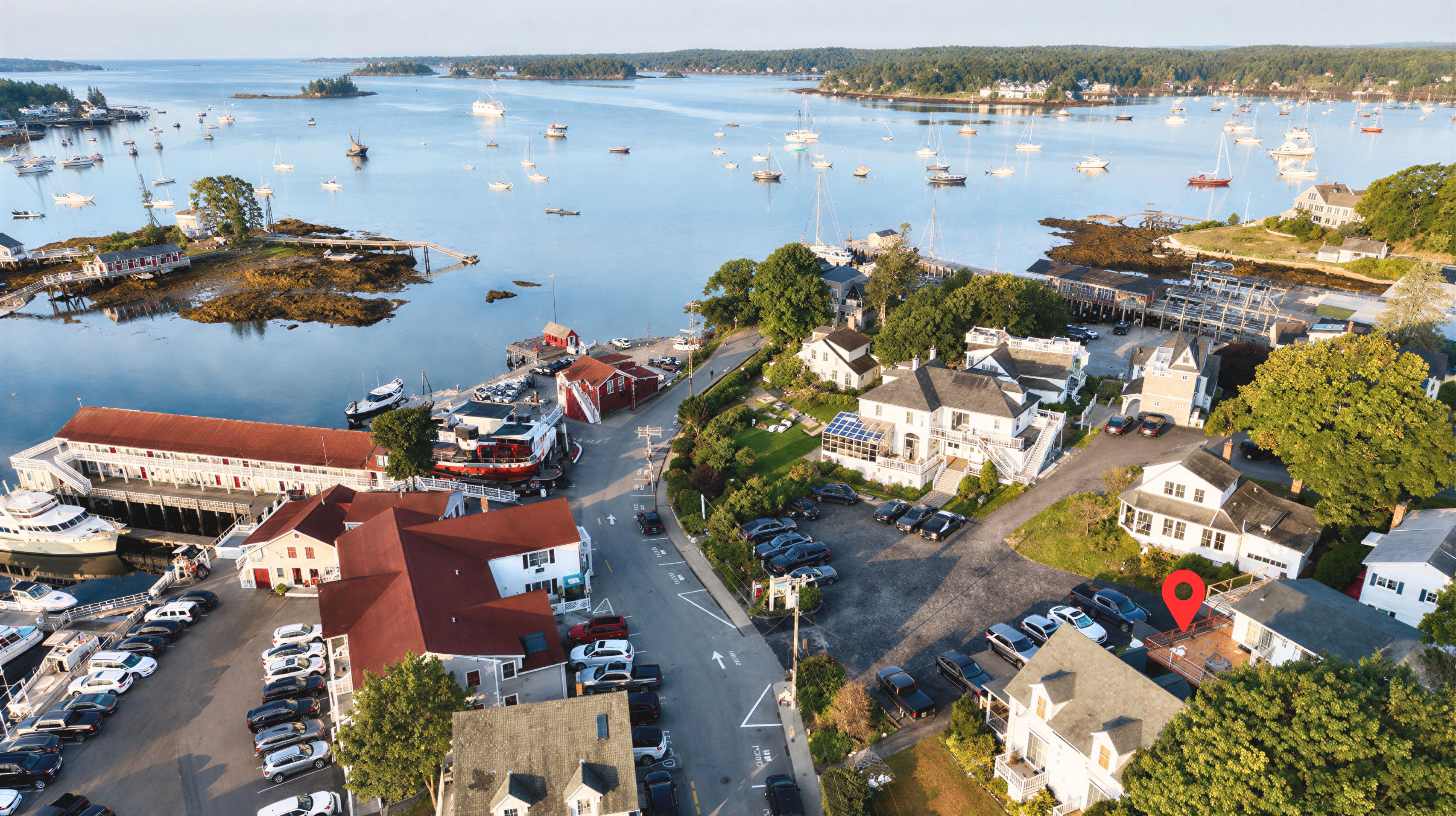 A coastal town with a marina, waterfront buildings, and parked cars.