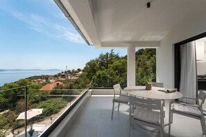 A balcony with a table and chairs, overlooking a coastal landscape. - Casa Meer an sea-view retreat with panoramic pool (Zagorje)