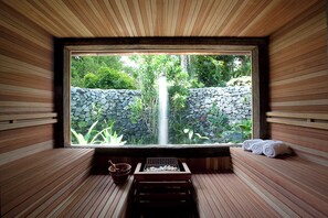 Una sauna de madera con pared de piedra y vistas a una cascada.