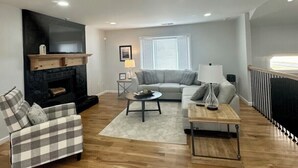 Una sala de estar moderna con chimenea, un sofá, una mesa de centro y un televisor montado en la pared.