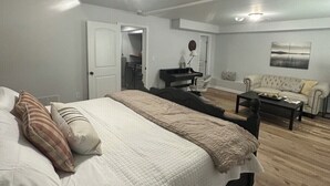 Un dormitorio con una cama grande, un escritorio, una silla, un sofá y un cuadro en la pared.