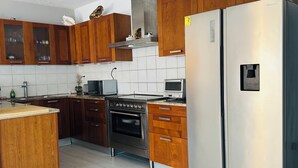 Et køkken med træskabe, et rustfrit stål køleskab, en mikrobølgeovn, en ovn og en gasblus.