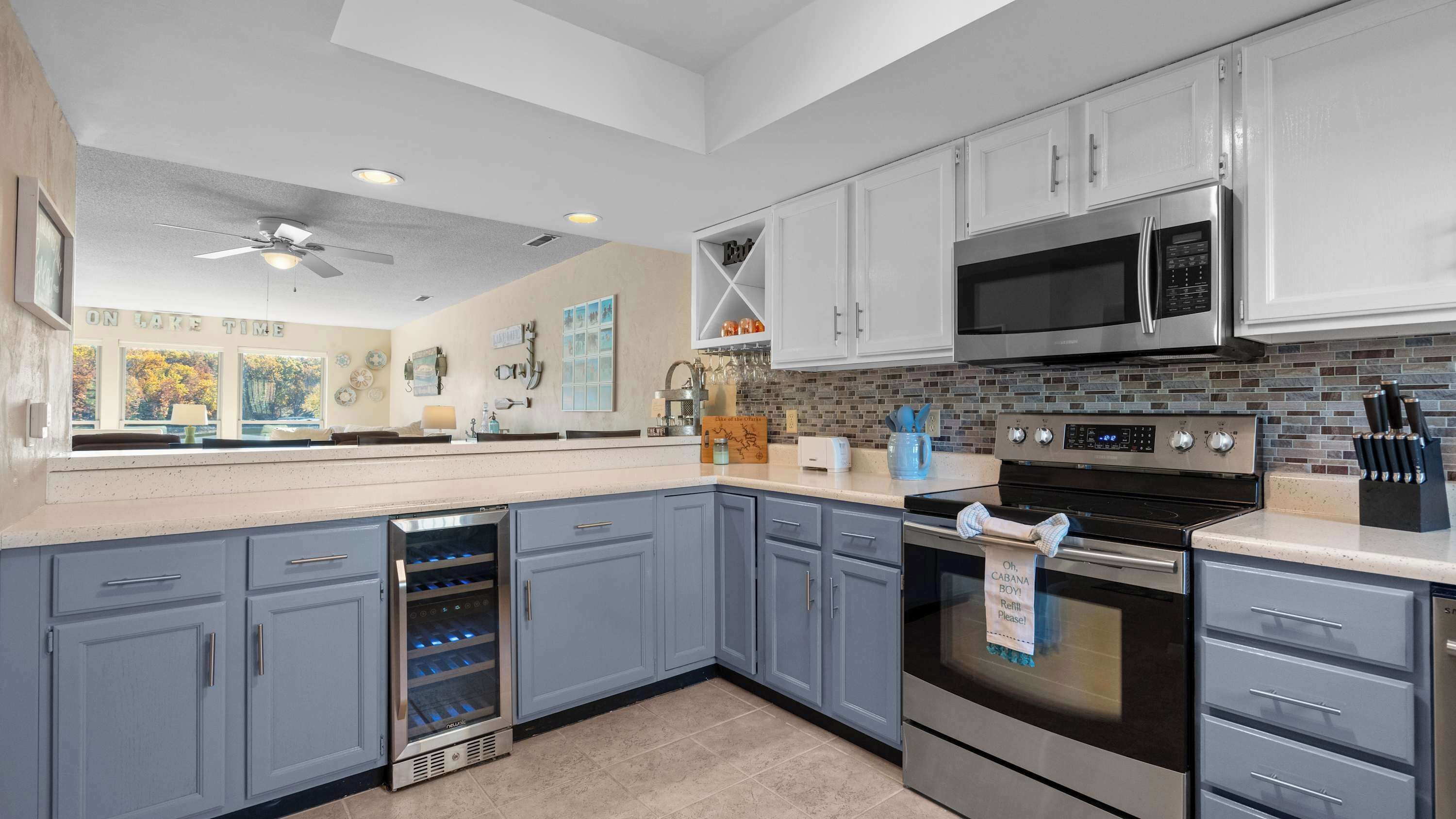 A modern kitchen with grey cabinets, stainless steel appliances, and a backsplash of small tiles.