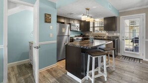 Een moderne keuken met een centraal eiland, roestvrijstalen apparatuur en een lichtblauwe wand.