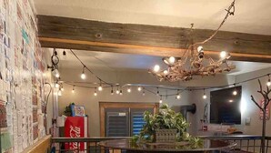 Un intérieur rustique agrémenté d’un grand tonneau en bois servant de pièce maîtresse, de guirlandes lumineuses et d’un vieux réfrigérateur Coca-Cola.