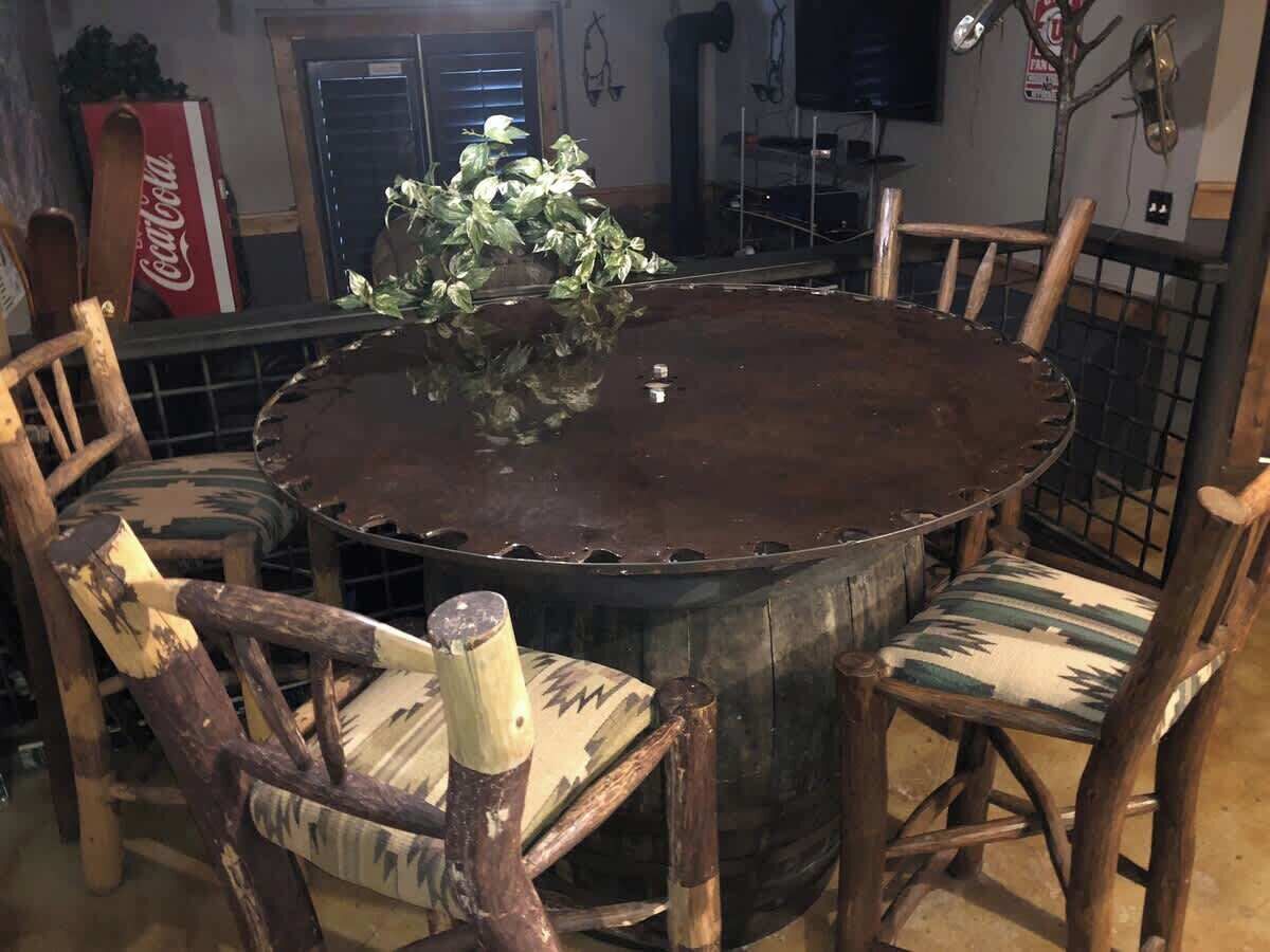 A rustic wooden dining table surrounded by mismatched chairs with a potted plant on top.
